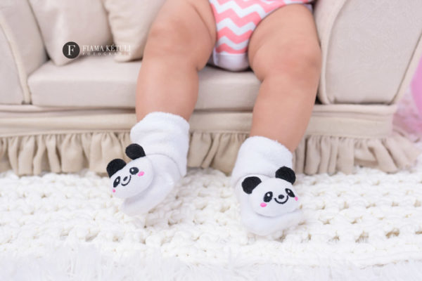 Foto do pézinho do bebê com meia de panda em estúdio fotográfico
